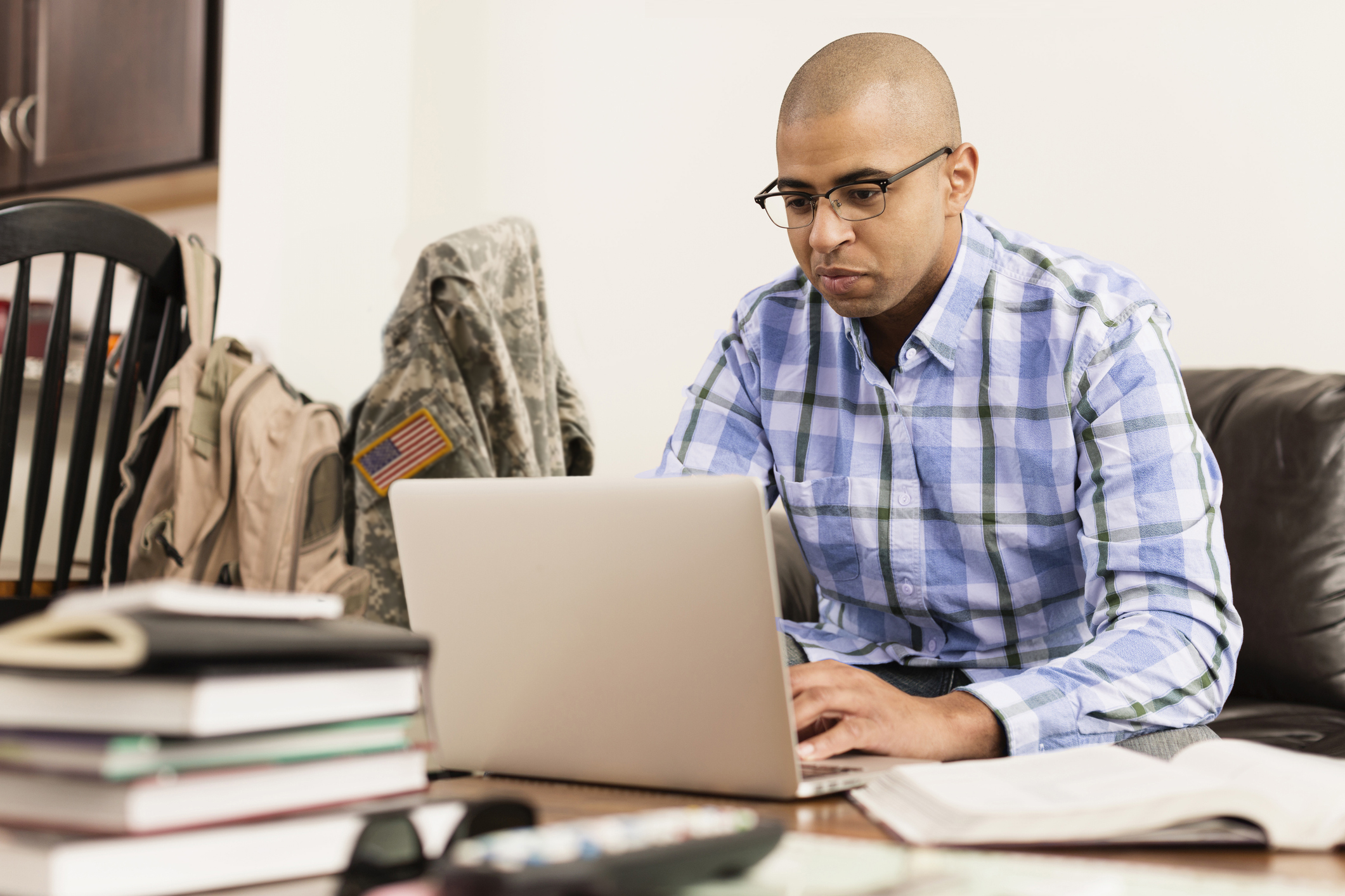 Mixed race soldier using laptop on living room sofa